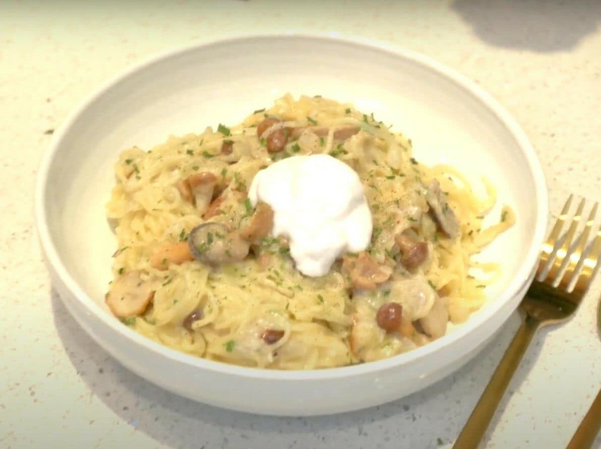 A plate of pasta with mushrooms with a non-dairy creamy sauce served with coconut yogurt for the Eat Burn Sleep lifestyle plan.