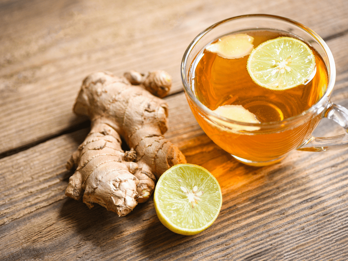 a cup of ginger tea with lemon slices and a side of ginger root