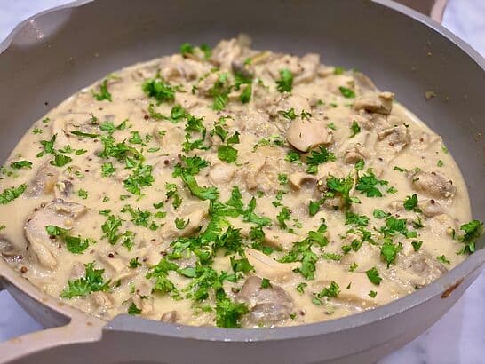 A pan filled with chicken in a creamy sauce with parsley on top, which is part of a gut-friendly diet.