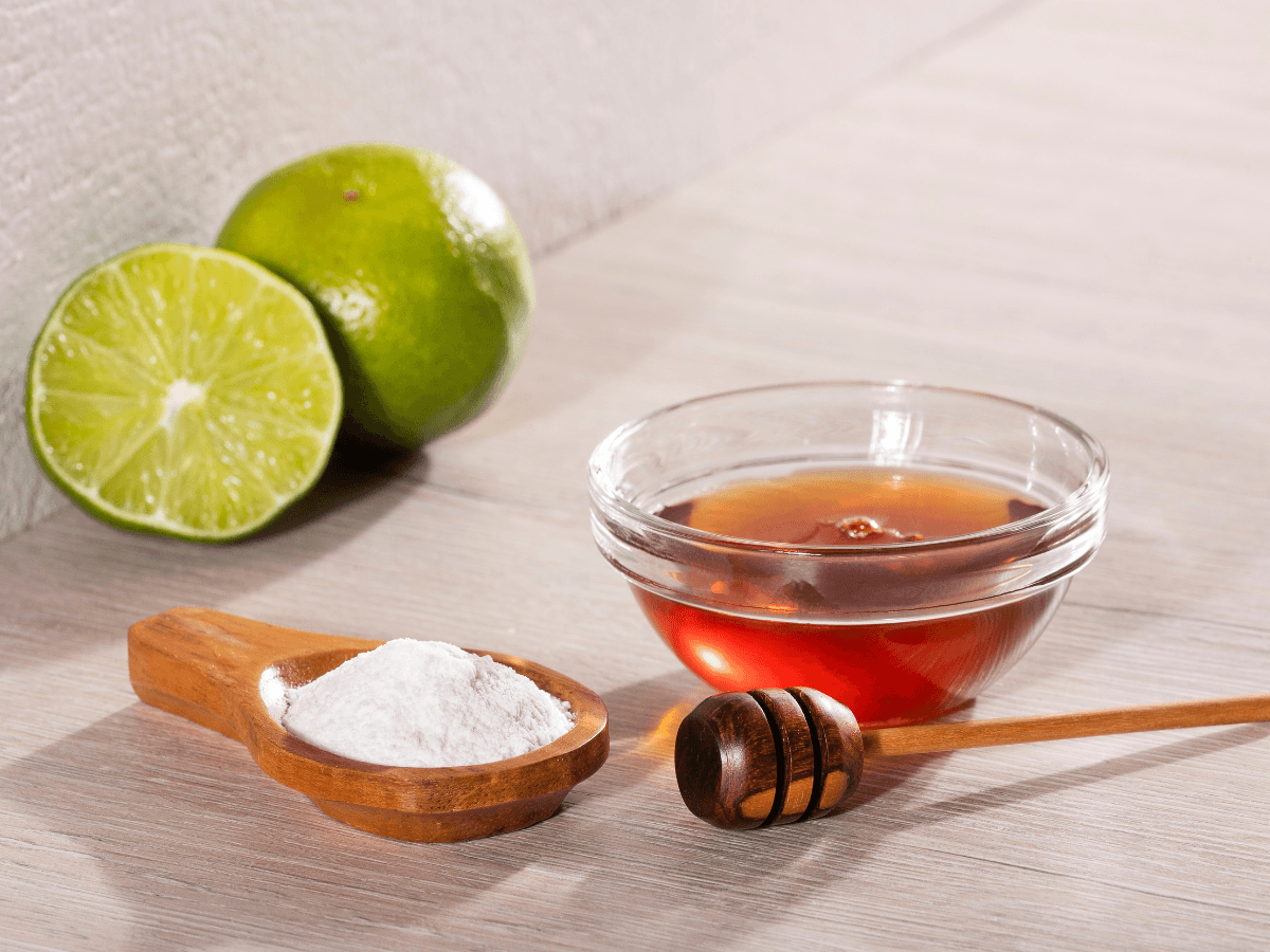 A bowl of honey, with a bowl of white powder and a halved lime.