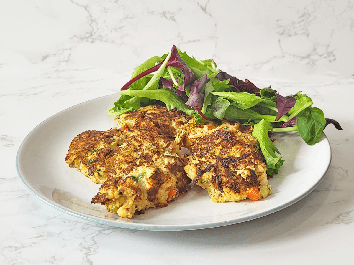 plate with crab cakes and a side of salad leaves